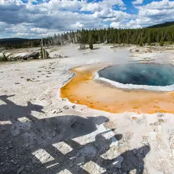 A steaming hot spring in Yellowstone National Park, glowing with vibrant blue, orange, and white mineral layers. In the foreground, shadows cast on the ground resemble iconic Star Wars characters from a galaxy far, far away. A steaming hot spring in Yellowstone National Park, glowing with vibrant blue, orange, and white mineral layers. In the foreground, shadows cast on the ground resemble iconic Star Wars characters from a galaxy far, far away.